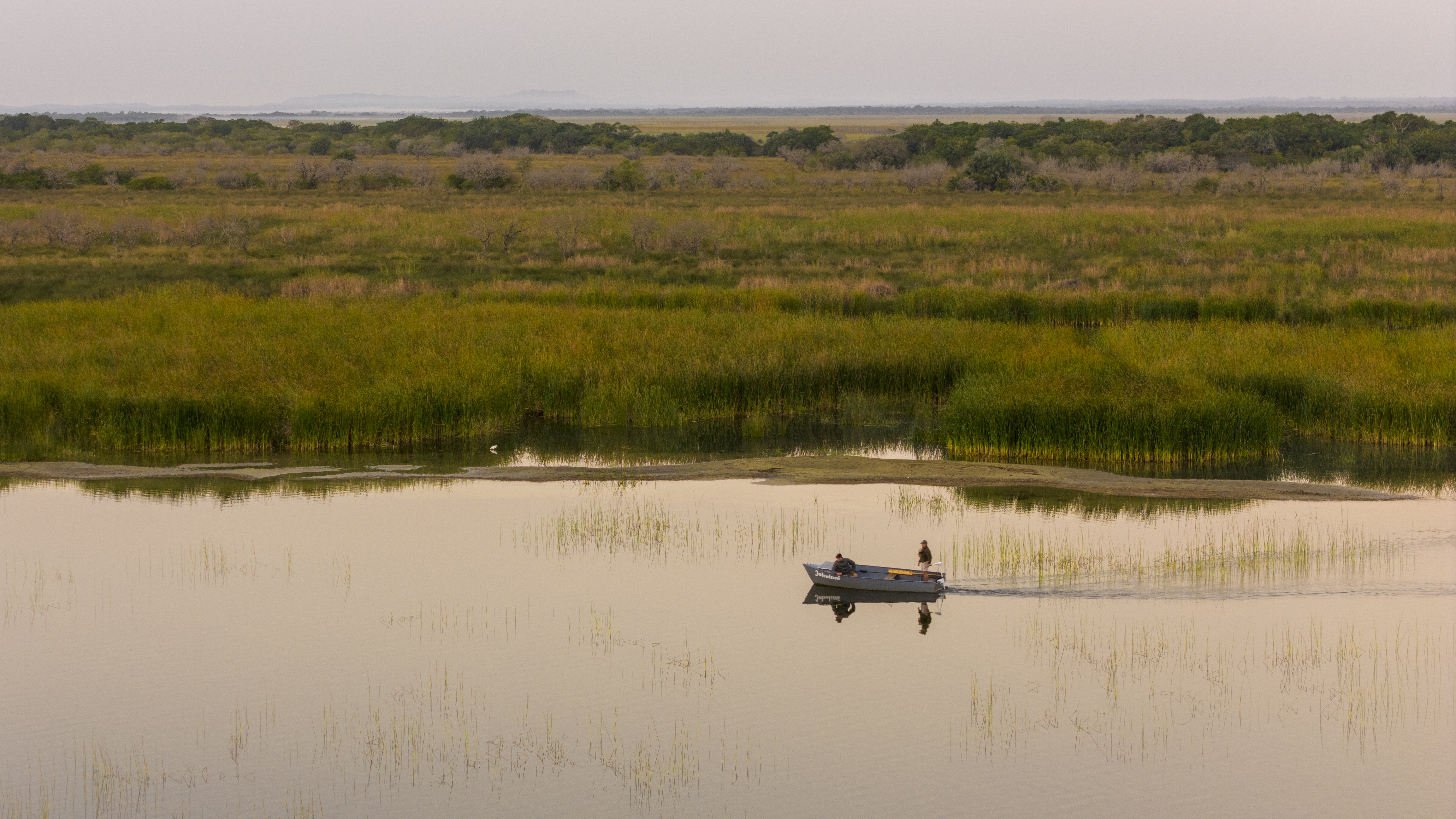 A boat crossing a lake at first light